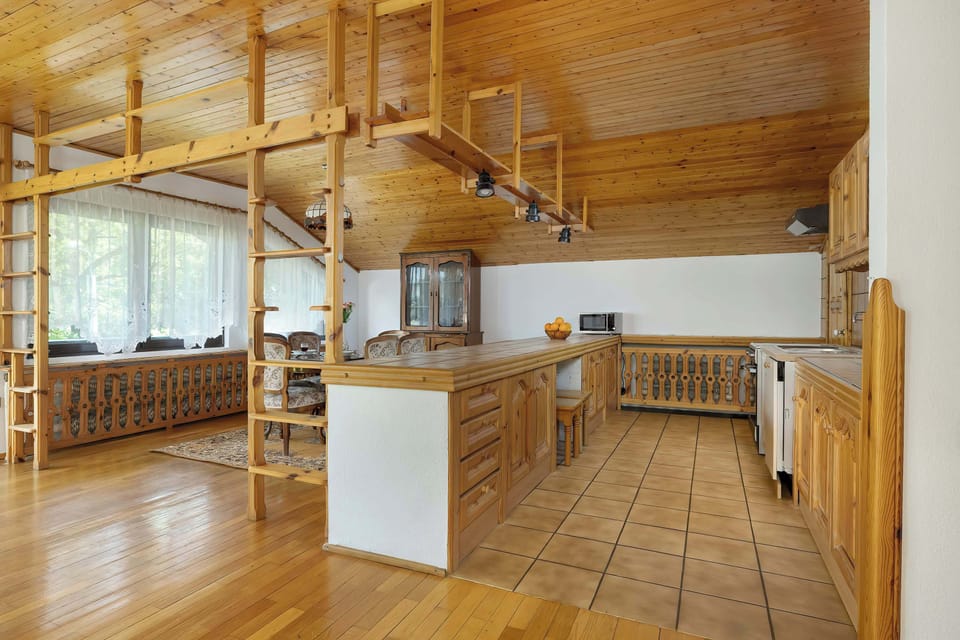 Traditional wooden kitchen with tiled backsplash, dining table, and ceiling beams, ideal for countryside home stays or alpine retreats.