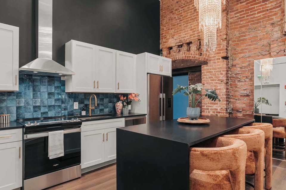 The fully stocked kitchen features a stunning chandelier, state-of-the-art appliances, and a sleek island with three plush, upholstered seats—perfect for casual dining or morning coffee.