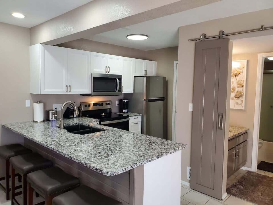 Side view of the newly remodeled kitchen with four comfortable bar chairs.  Beautiful granite top, all new ss appliances.