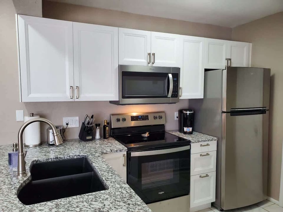 Full kitchen view with Freezer/Fridge w/ ice maker, Keurig Coffee Maker, Microwave, Electric Stove Top/Oven, Knife Set, Toaster, Dishwasher, and Kitchen Faucet w/ Sprayer.  