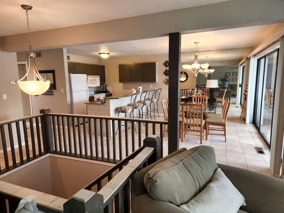 A look into the kitchen area with the dining room and breakfast bar. U-shaped steps lead down to the lower level in the center. 
