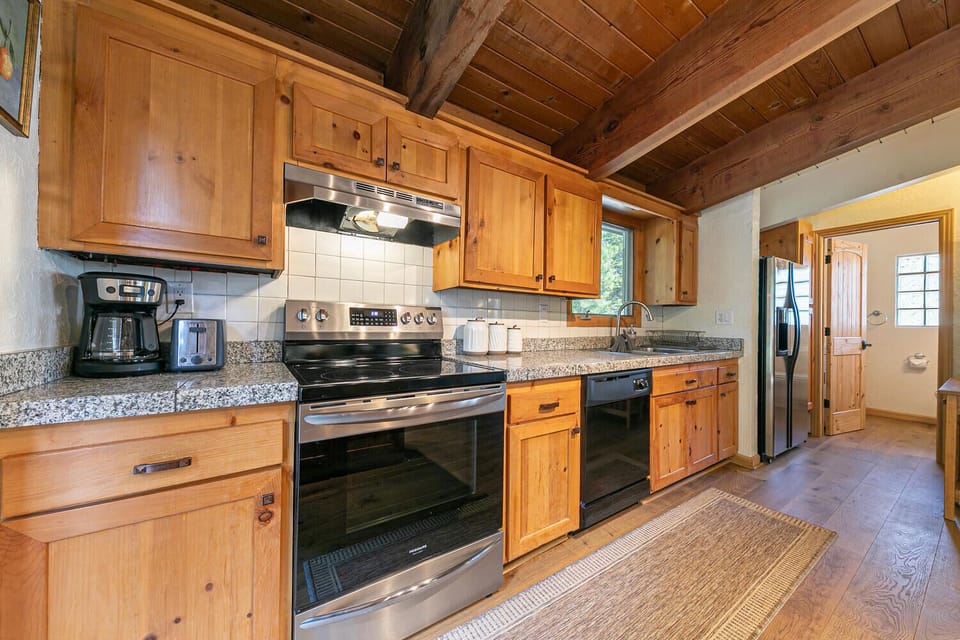 Fully equipped kitchen with stainless steel appliances, granite countertops, and rustic wood cabinets perfect for home-cooked meals.
