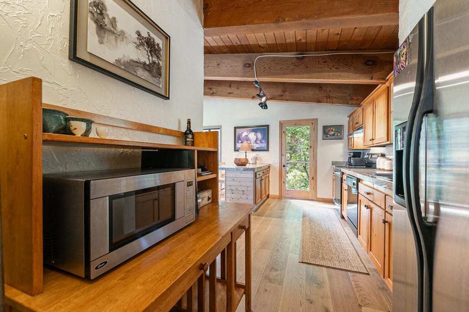 Spacious kitchen with stainless steel appliances, microwave station, and warm wood finishes perfect for cooking and gathering.
