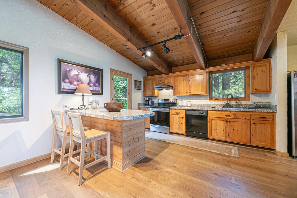 Fully equipped kitchen with stainless steel appliances, granite counters, and a cozy breakfast bar ideal for morning coffee or casual meals.