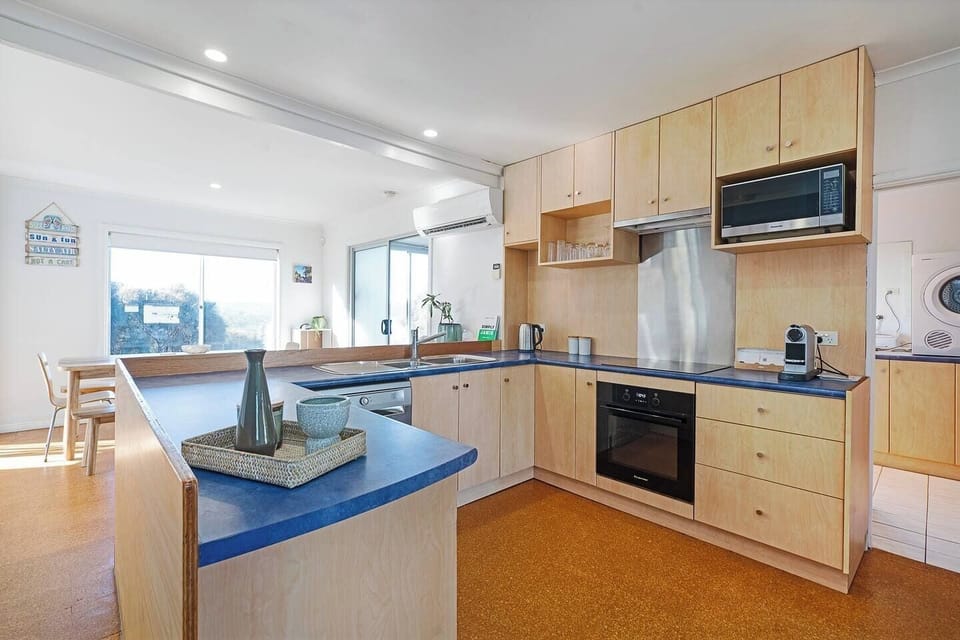 A bright, functional kitchen with retro charm—complete with ocean glimpses, timber cabinetry, and all the essentials for home-style meals.