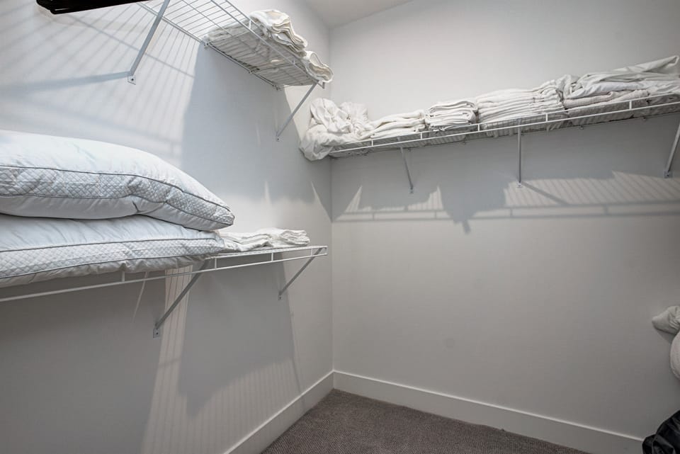 Relax in the serene master bedroom featuring a comfortable king-size bed, soft linens, and cozy pillows. Includes nightstands, lamps, walk-in closet, and full-length mirror for added comfort. 