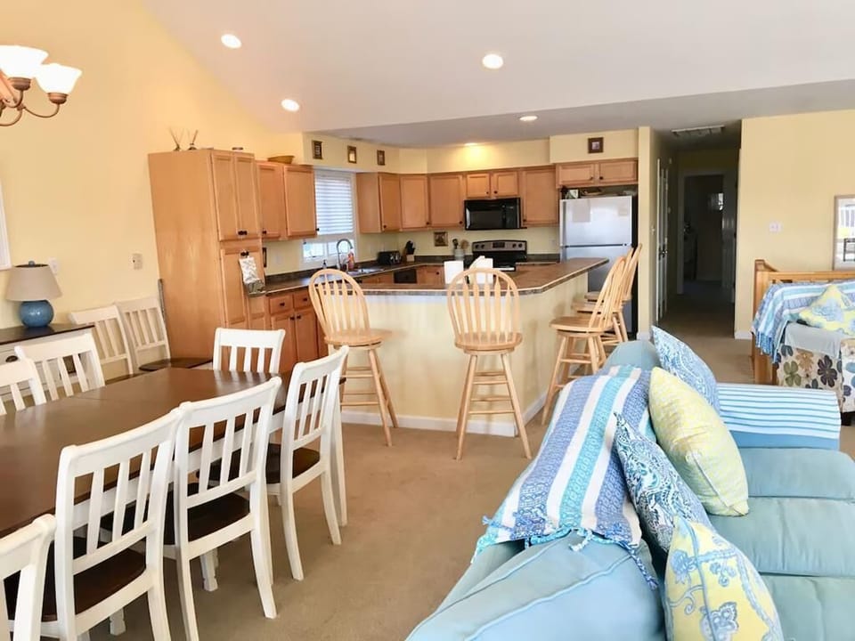 The spacious open-concept living and dining area features a large table for group gatherings, alongside a well-equipped kitchen that boasts bar seating.