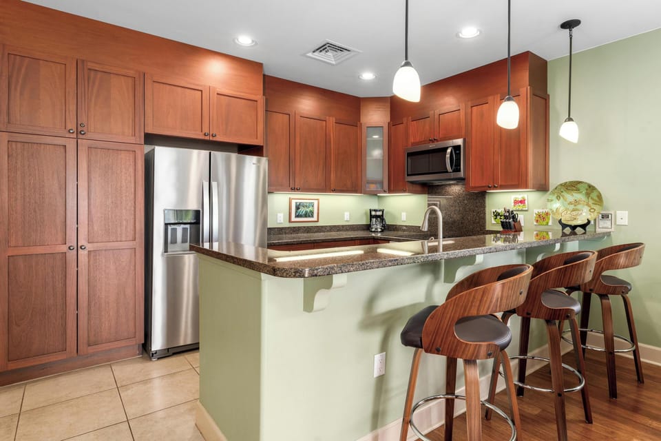 Full kitchen with breakfast bar, granite counters, and stainless steel appliances