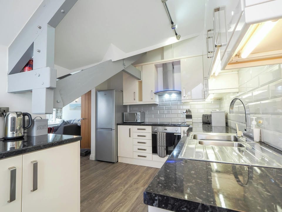 Underneath of the staircase, sink, worktop, kettle, fridge, freezer and wall cabinets