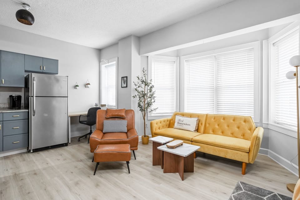 Bask in natural light from the bay windows as you unwind in this thoughtfully styled lounge—complete with a tufted sofa, mid-century chair, and soft accents that make relaxation effortless.