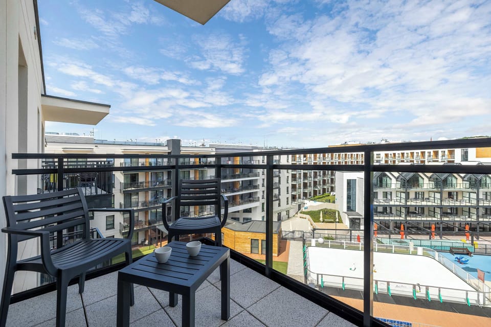  A spacious balcony overlooking the swimming pool and a blue sky filled with clouds is a perfect spot for outdoor relaxation.