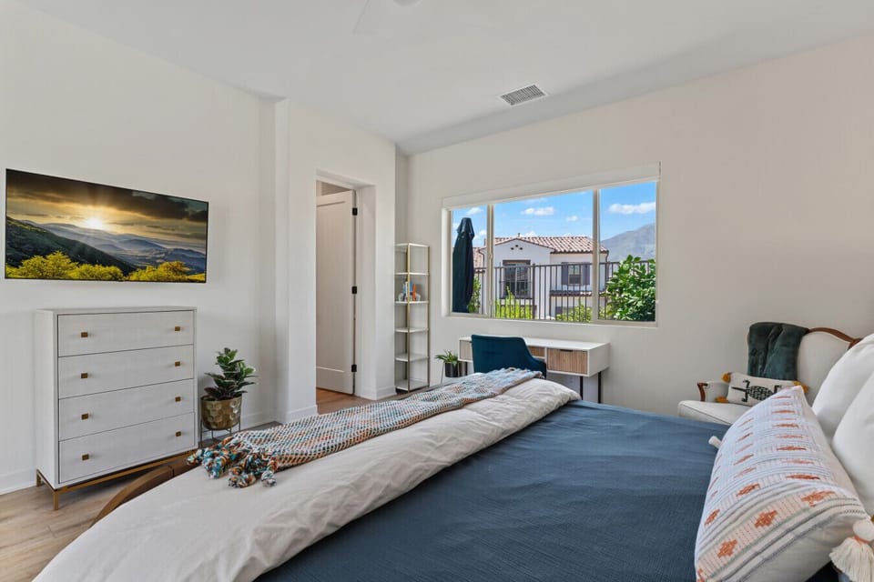 Serene bedroom w/ large windows, dresser & soft natural light