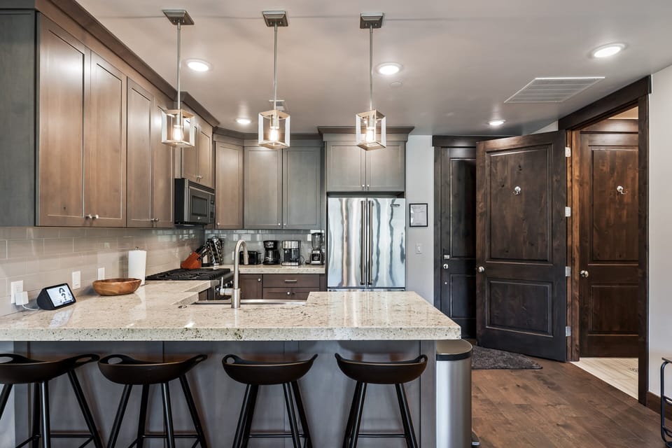 - Fully equipped kitchen with stainless steel appliances  
- Bar seating for morning coffee or evening drinks  
- Pendant lighting highlights the spacious counters