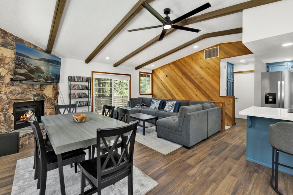 Cozy mountain living room with a stone fireplace, comfy seating, and smart TV—perfect for relaxing evenings, movie nights, and warm cabin vibes after outdoor adventures.