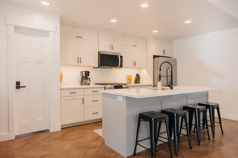 Kitchen featuring recessed lighting, stainless steel appliances, a center island with sink, light stone counters, and a breakfast bar area