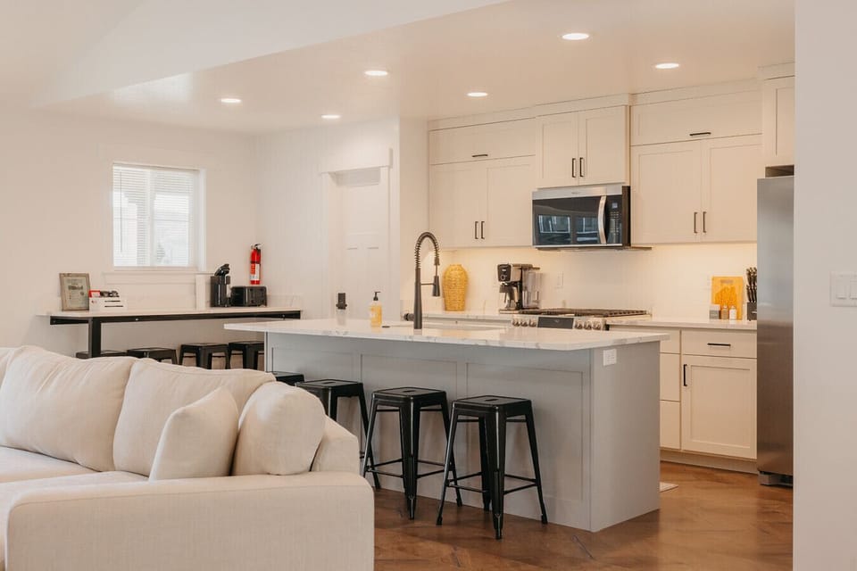 Kitchen featuring recessed lighting, stainless steel appliances, a center island with sink, light stone counters, and a breakfast bar area