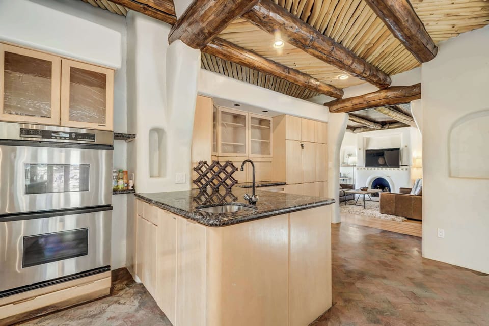 The open-concept kitchen includes double ovens, granite counters, and a prep sink—perfect for cooking and entertaining just steps from the cozy living room and fireplace.
