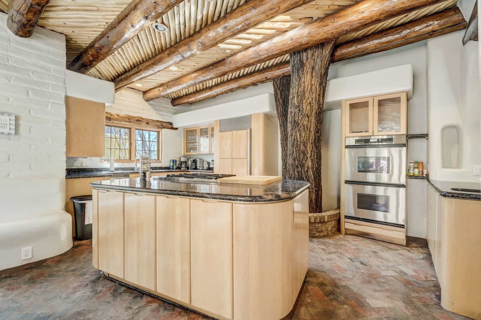 Behold, our kitchen masterpiece! From the expansive center island with a granite top to the fully stocked cabinets, stove, and charming live tree, every detail is designed for culinary delight..