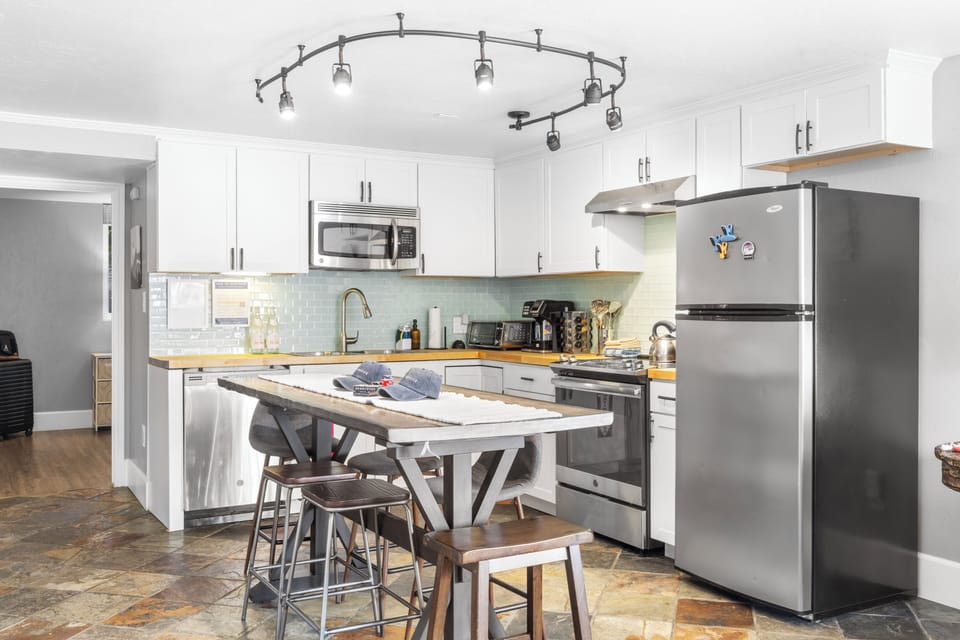 Fully equipped kitchen with barstool seating and stainless steel appliances.