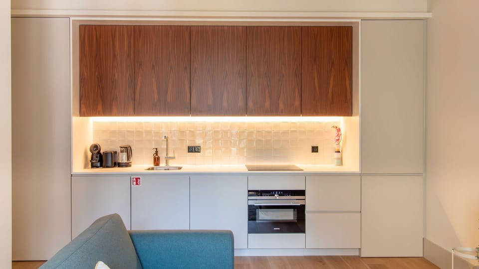 Fully equipped kitchenette with warm wood finishes, sleek appliances, and modern lighting—perfect for cooking in style. #DesignKitchen #ModernComfort #LovelyStay