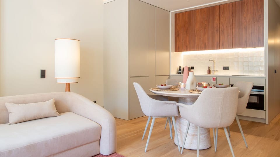 Cozy meets contemporary in this open-plan kitchen and lounge, complete with designer furnishings and soft lighting for a warm, welcoming vibe. #ModernComfort #LisbonStay #OpenPlanLiving #LovelyStay