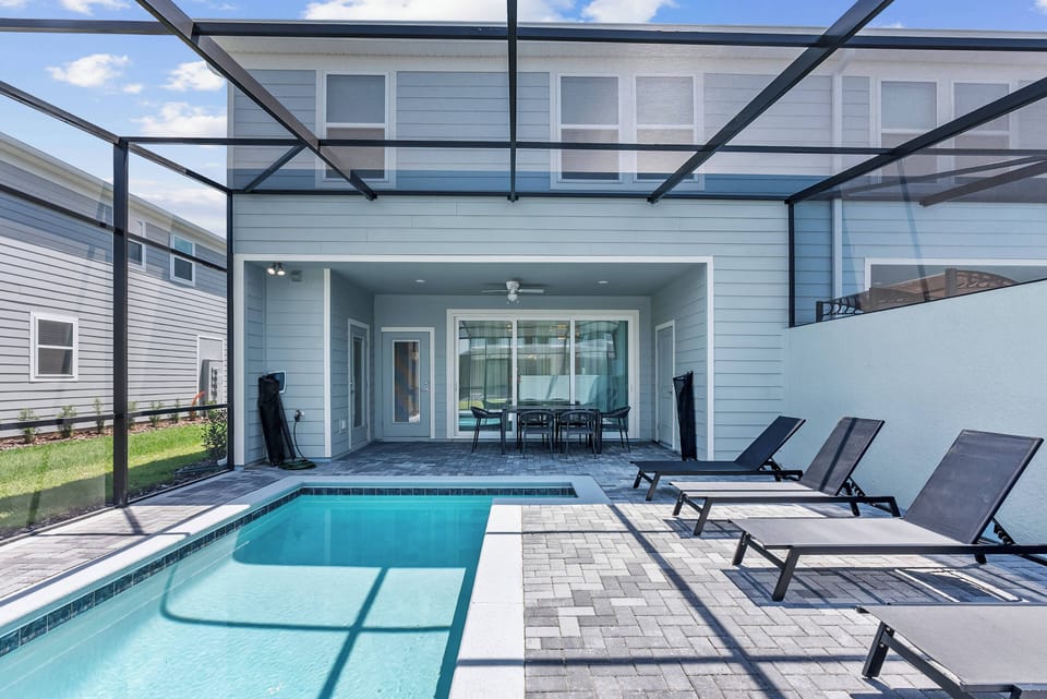 Step outside to the inviting pool area, featuring sleek lounge chairs by the crystal-clear water. The modern patio, enclosed for style, creates a seamless flow from indoor to outdoor living, ideal for your relaxation.