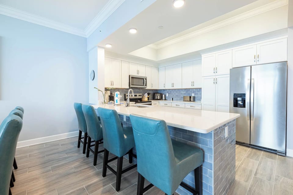 Gather around the stylish kitchen bar with teal seating, perfect for casual meals and conversations
