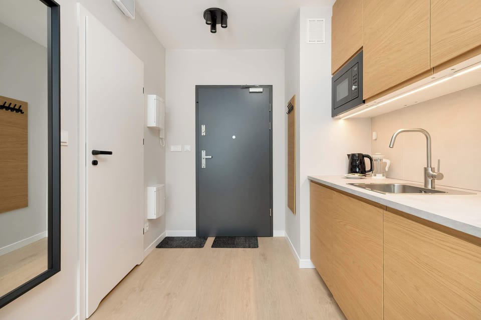 A mirror image of the earlier kitchen view with a light wood finish, stove, and overhead cabinets.