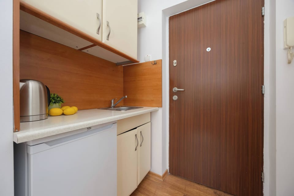 A modern kitchenette with white cabinets, a wooden countertop, and stylish lighting, perfect for preparing everyday meals.
