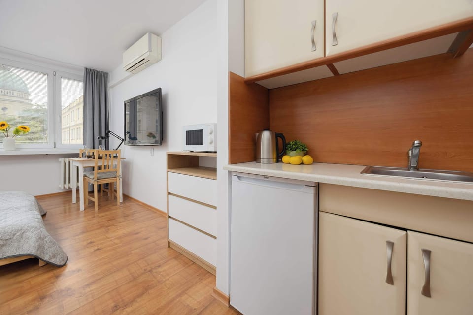 A modern kitchenette equipped with white appliances, including a fridge and stove, and elegant cabinets above the wooden countertop.