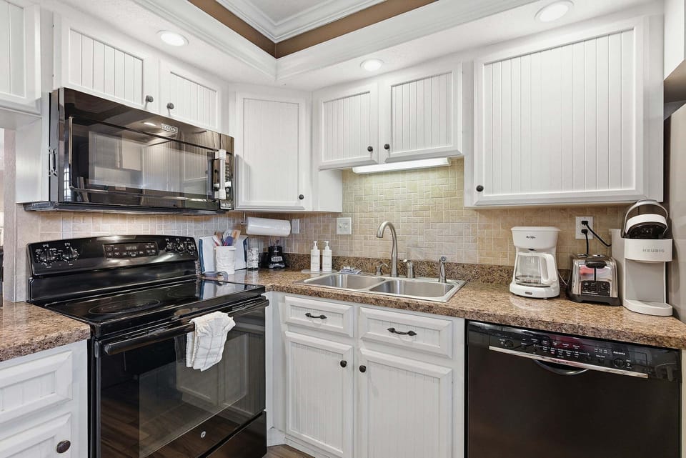 Clean, coastal kitchen with modern appliances, coffee maker, and ample counter space. Perfect for your beach stay, prepare meals with ease and enjoy the comfort of a well-stocked space after a day by the ocean.