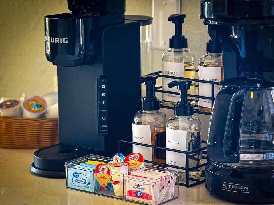 Fully stocked coffee bar with Keurig, drip brewer, syrups, and premium morning essentials.