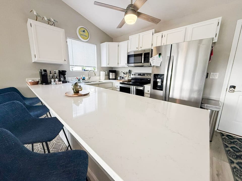 Bright, fully equipped modern kitchen with quartz island, stainless appliances, and coffee bar—perfect for lake getaways.