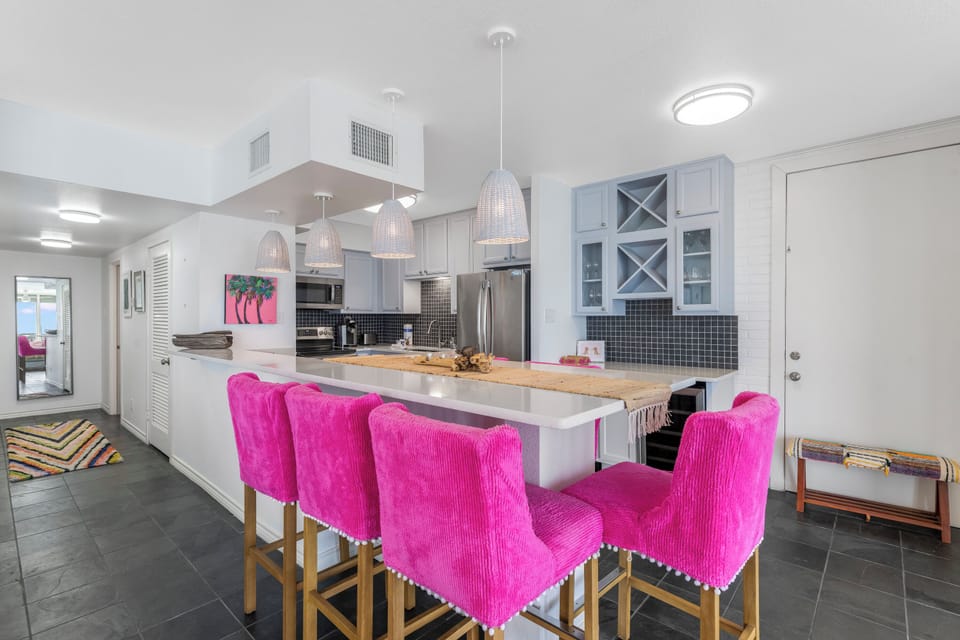 Cook and gather around this stylish kitchen island featuring vibrant pink bar stools and modern appliances for memorable meals together.
