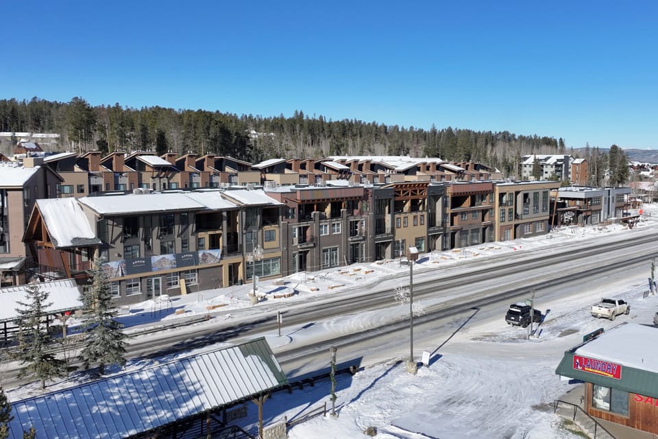 A winter mountain resort community featuring modern condominiums and townhomes nestled among snow-covered forests.