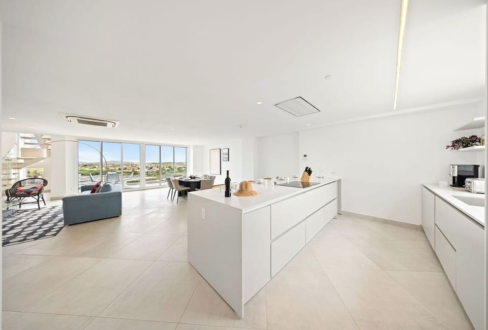 Modern open-plan living where your stylish kitchen flows into a bright lounge with sweeping sea views through floor-to-ceiling windows.