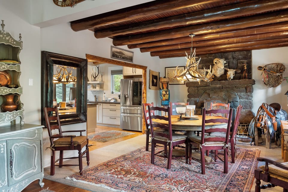 - Dining space with stone fireplace and wood accents highlighting charm   - Round wood table with classic chairs invites shared mountain meals   - Rustic details and open flow make this a welcoming gathering area