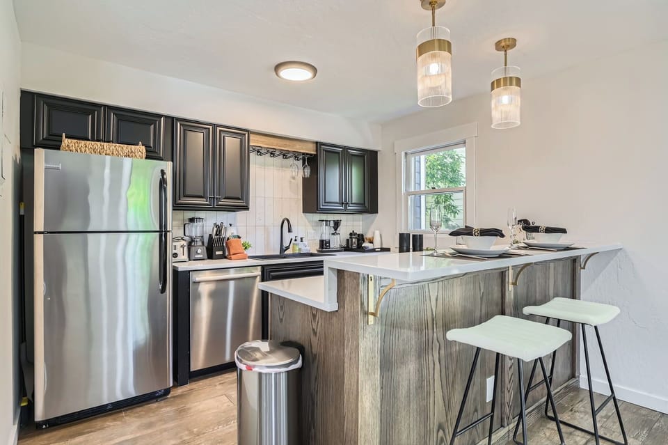 Modern fully-equipped kitchen with stainless steel appliances, dark cabinetry, and a spacious island with bar seating. Perfect for preparing meals during your stay.