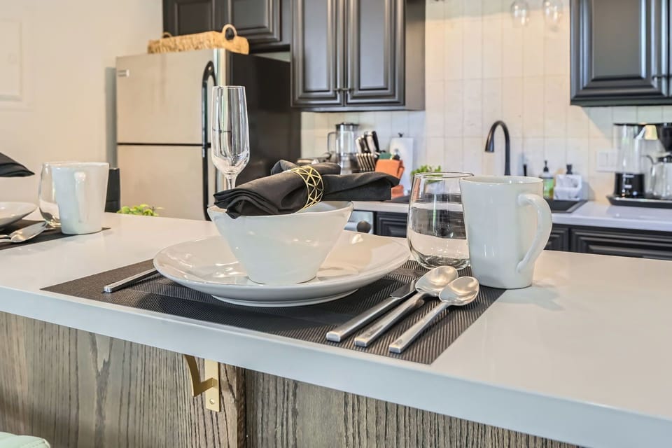 Modern & clean kitchen with dark cabinetry, sleek countertops, and bar seating for a quick snack during your stay.