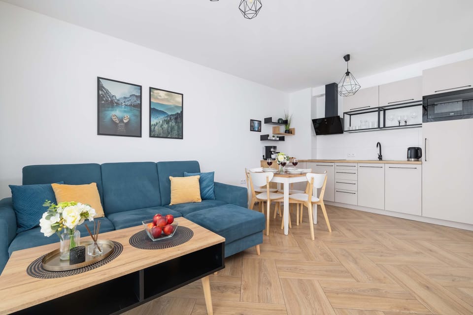 A cozy living room with a blue sofa, wooden table and chairs combines comfort with functionality.
