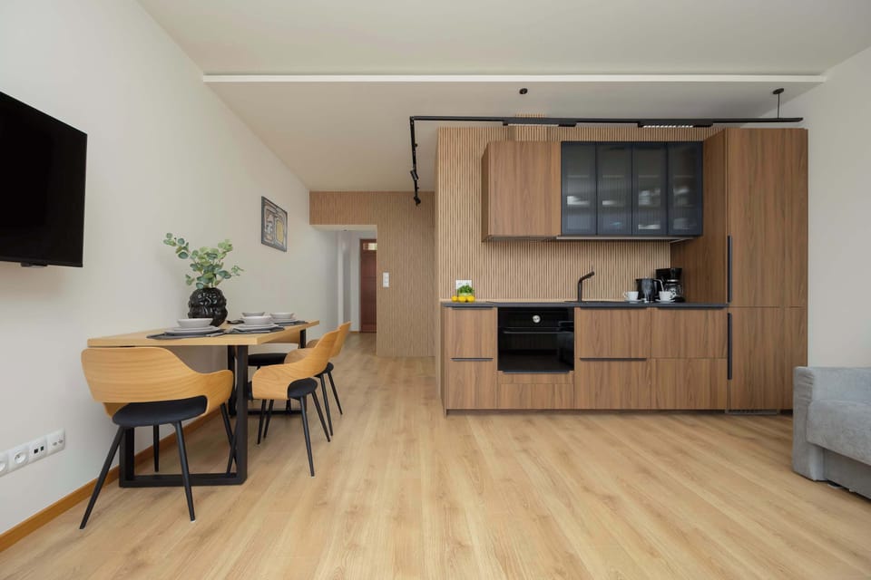 Full kitchen with wooden cabinetry, black appliances, and a dining table.

