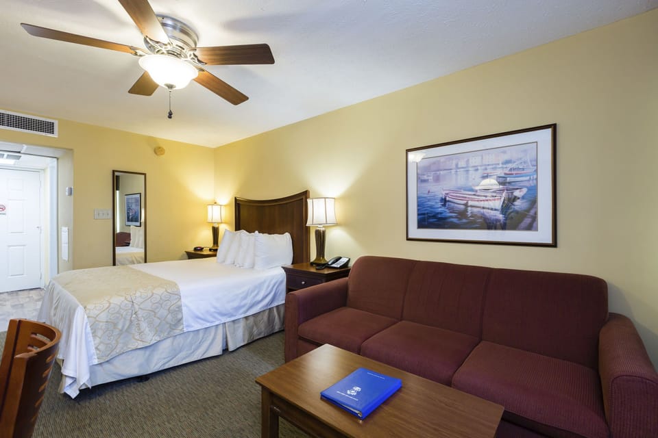 Comfortable studio setup with queen bed, sleeper sofa, and balcony access.
