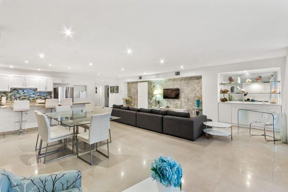 The bright, airy living room with turquoise accents and wall to ceiling windows overlooking the pool area.