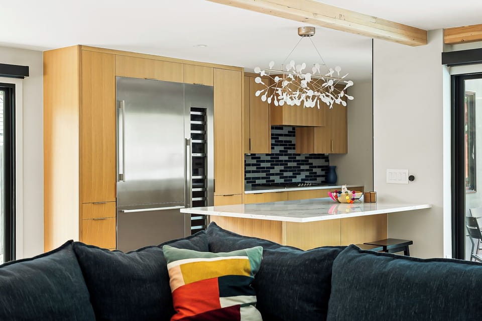 A cozy open kitchen layout with natural wood cabinetry and a sleek breakfast bar. The design is complemented by modern lighting and opens directly into the living area for seamless entertaining.