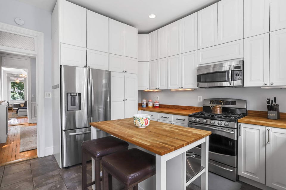 Kitchen with a view of the kitchen center table with chairs, stainless finish refrigerator, oven, stove and microwave, floor tiles, kitchen cabinets and a doorway leading to the dining area and living room