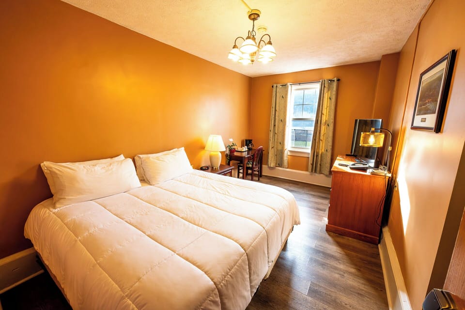 Relax into crisp bedding beside a sunny window workspace.