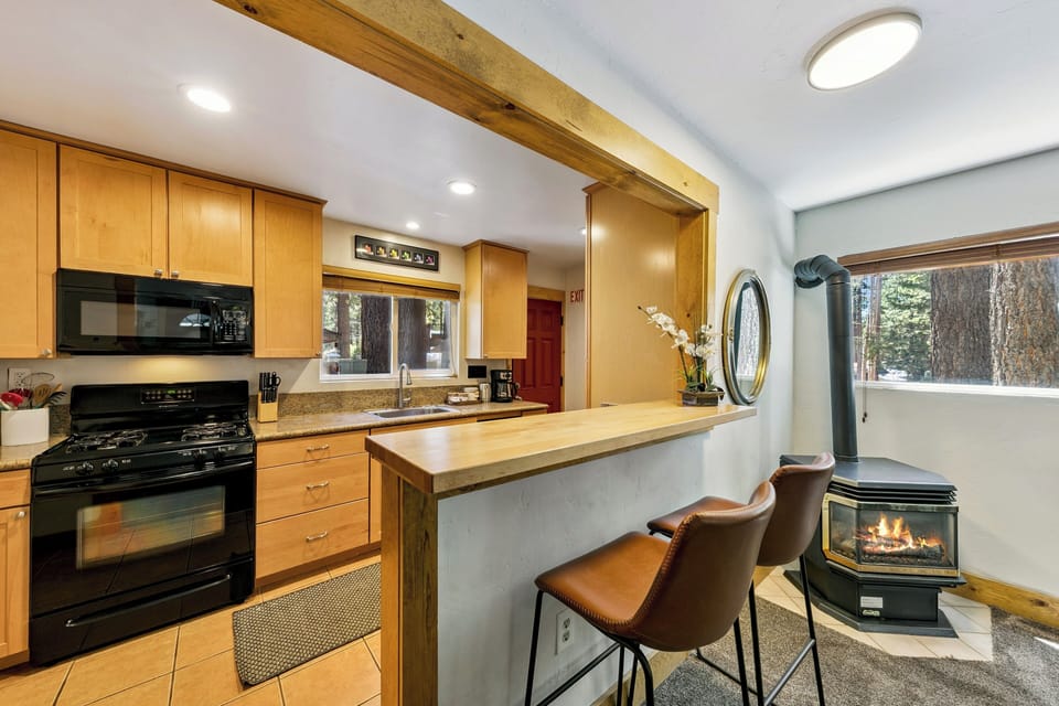 Gather around this warm kitchen island where exposed beams and crackling fireplace create the perfect atmosphere for your mountain getaway conversations.