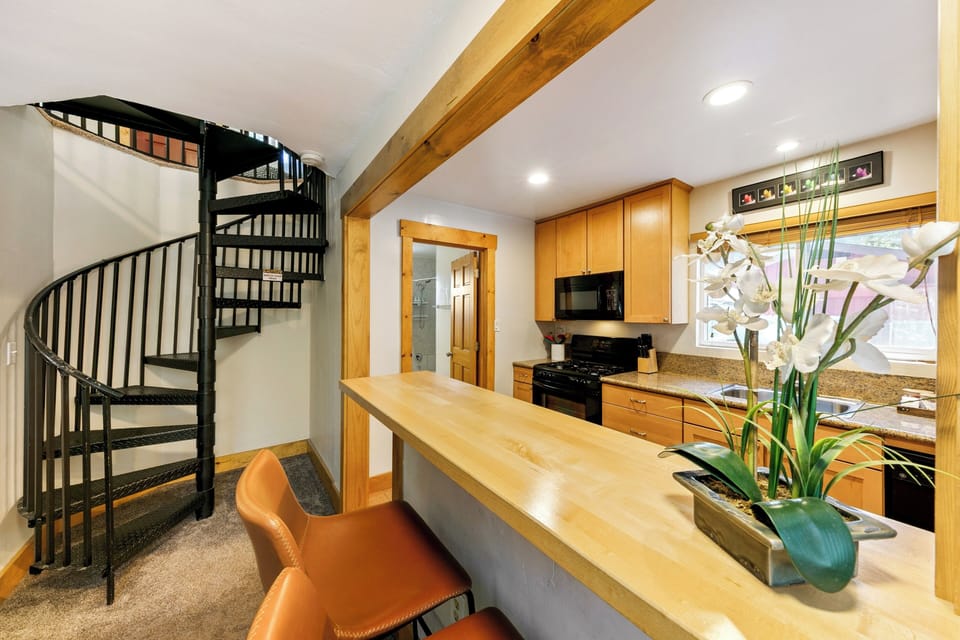 You'll love cooking in this stylish kitchen with warm wood tones and a unique spiral staircase adding architectural charm to your stay.