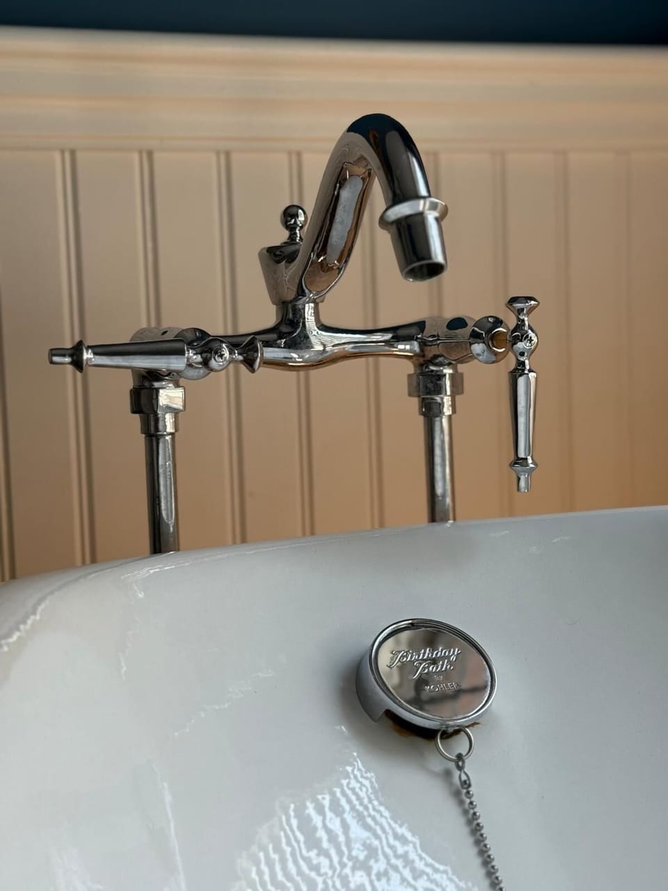 The Kohler Birthday Bath features chrome fixtures against wainscoted walls