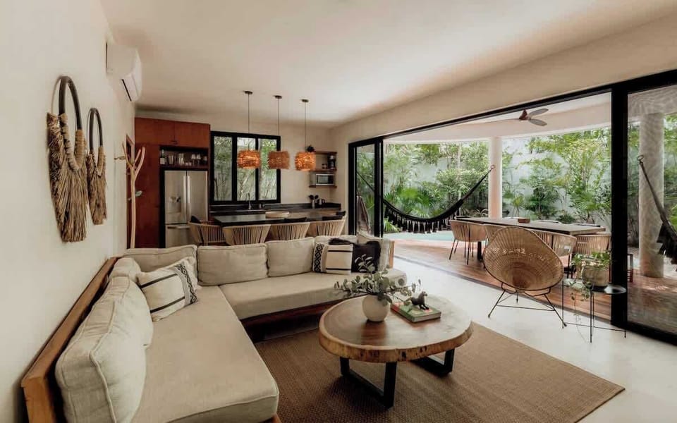 Open outdoor kitchen and bar with pendant lights, hammock, wood ceiling, and jungle views.
